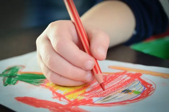 Ребёнок рисует карандашом.